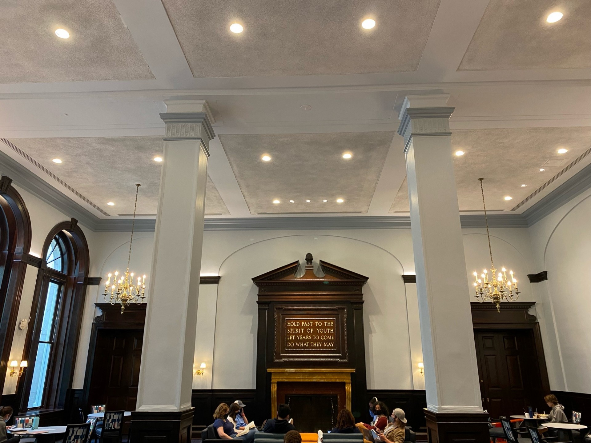 The fireplace and students sitting on couches in the John Jay Lounge