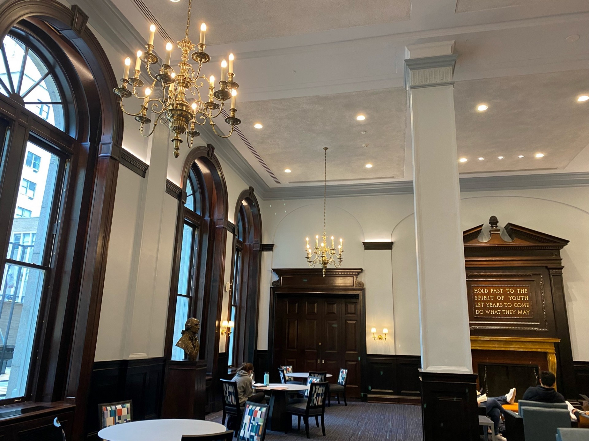 Round tables against a wall with windows in the John Jay Lounge