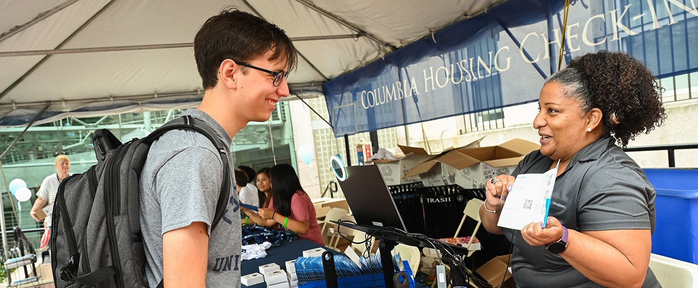 A Housing staff member helping a student check in