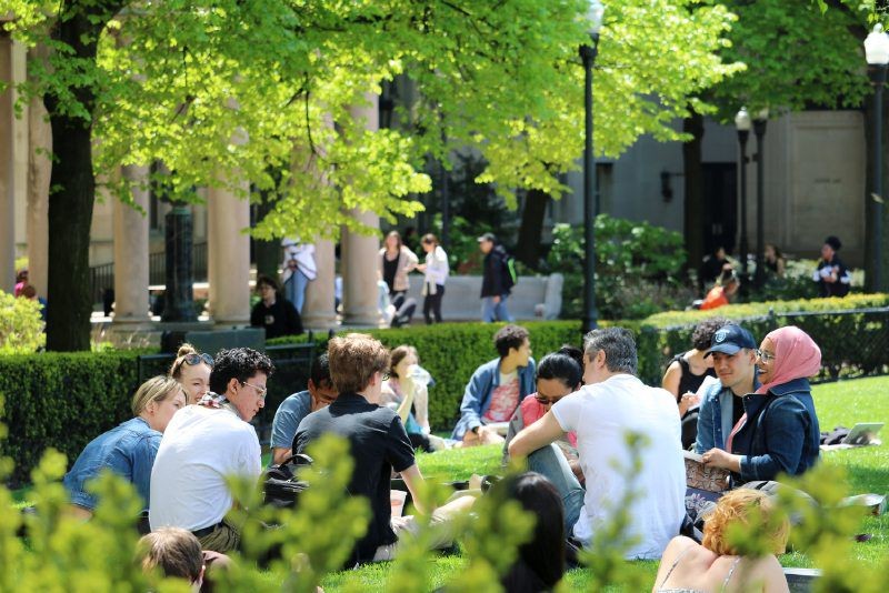 Students sitting in a circle on a grass lawn talking