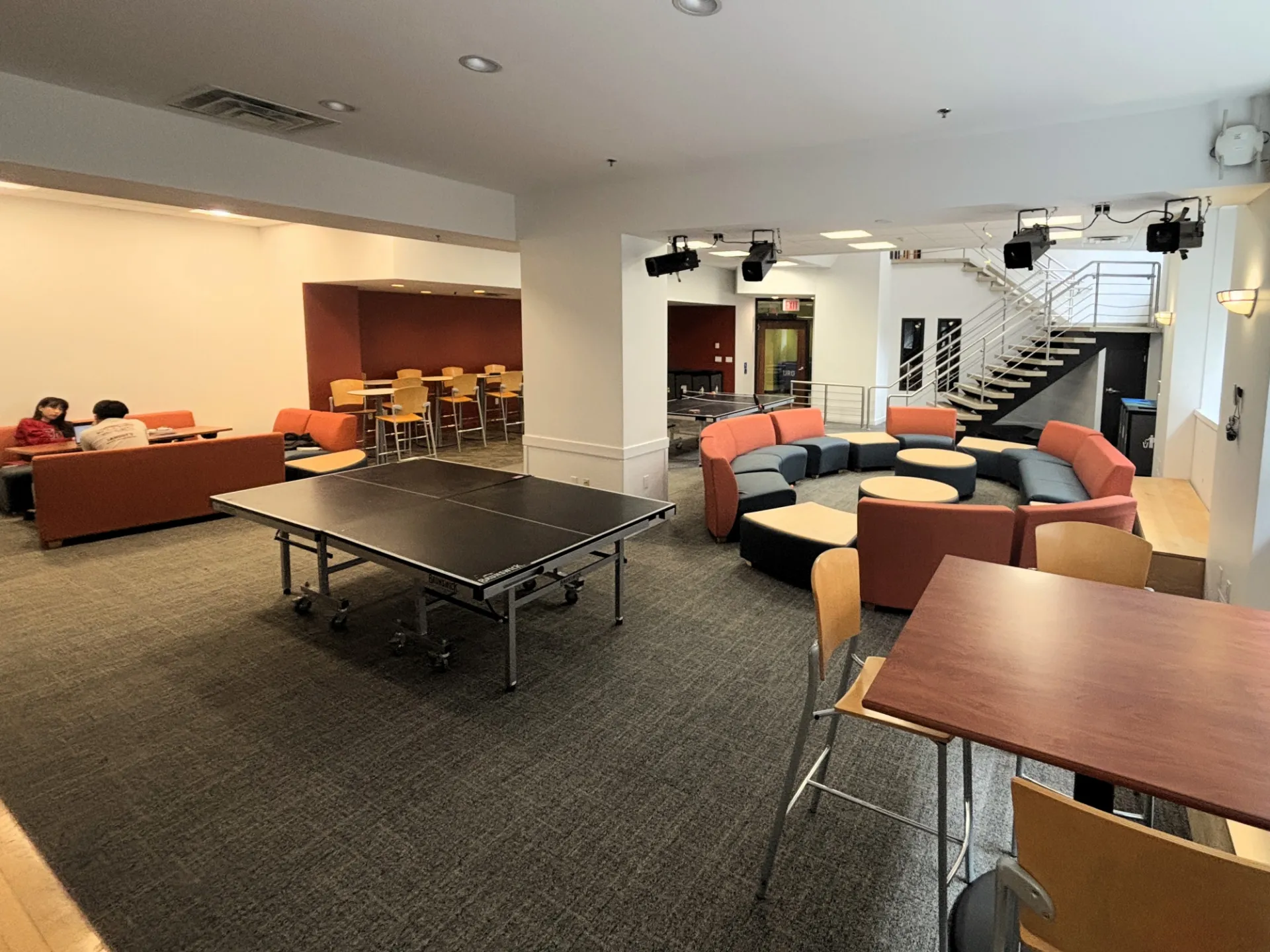 Carman Hall lounge with tables and chairs, lounge chairs, and ping-pong tables.