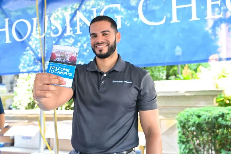 A Housing staff member holding the Check-In packet